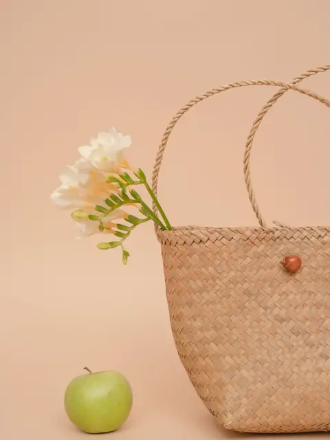 Woven basket bag with white flowers and a green apple