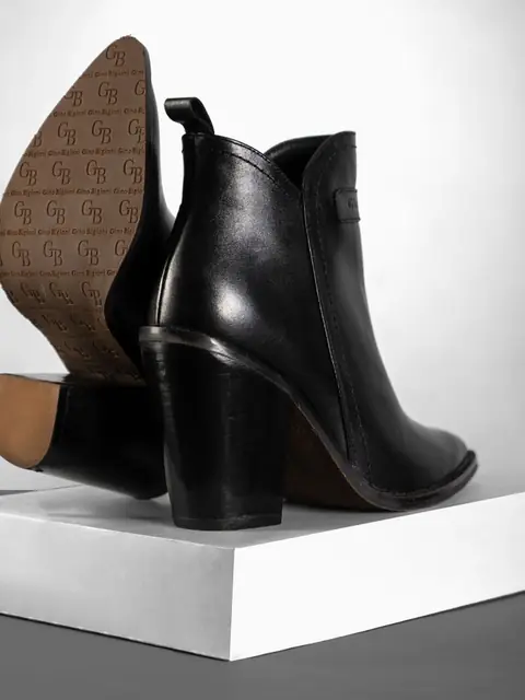 Black heeled ankle boot on a white plinth