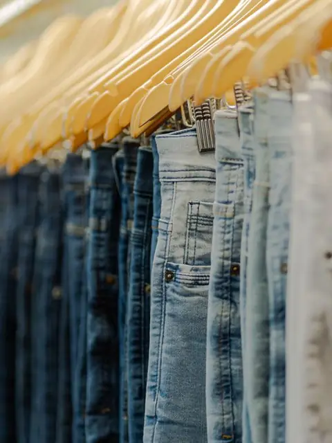 Row of blue jeans on wooden hangers