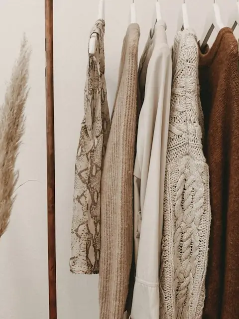 Neutral cardigans and knits hanging on a wooden rail