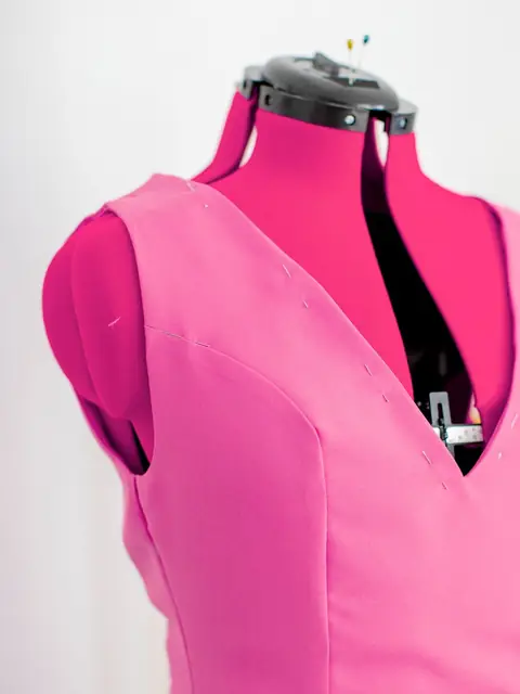 Hot pink fitted V-neck dress on a dress form
