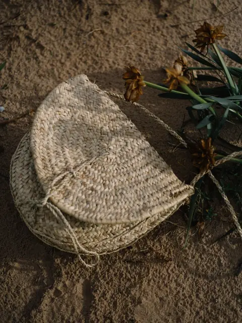 Half-moon woven straw clutch on sand