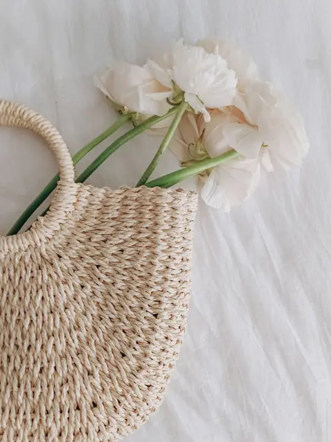 Woven straw tote holding white flowers