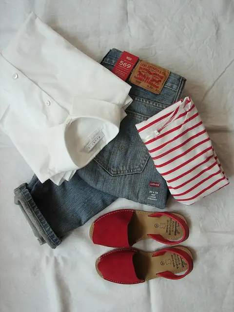 Flat lay of a red-and-white striped tee, white tee, cuffed jeans and red sandals